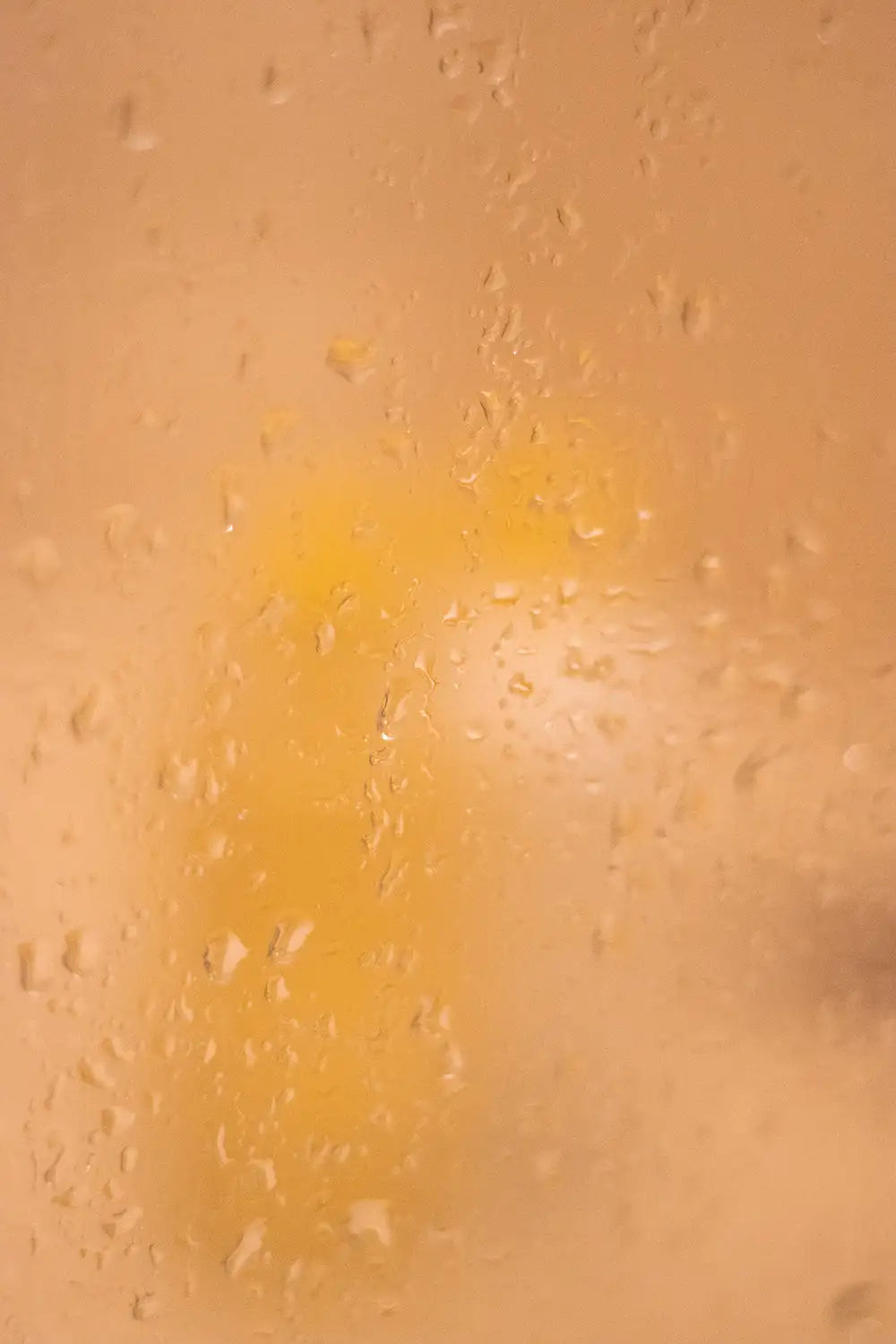Una imagen borrosa con tonos cálidos de un líquido amarillento con gotas en la superficie.