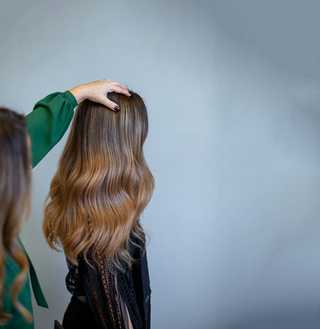 Person's hand on long, wavy ombre hair.