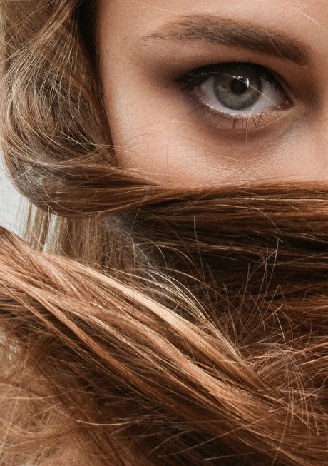 a close up of a woman's face with her hair blowing in the wind