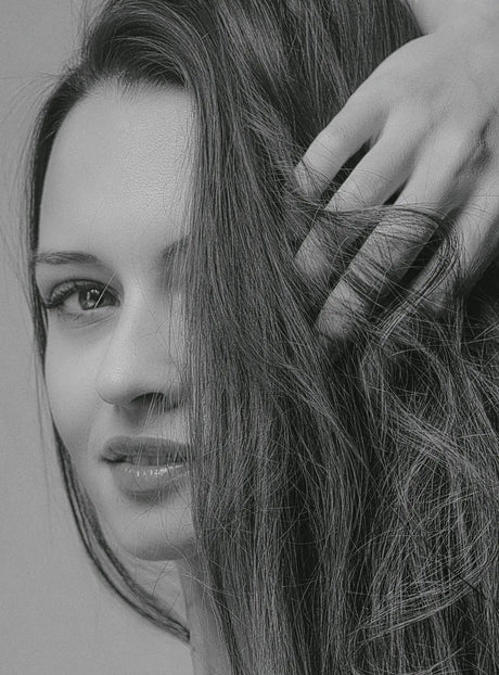 a black and white photo of a woman brushing her hair