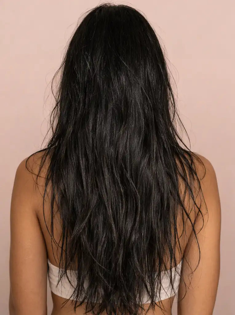 Cabello largo, brillante y negro con ondas naturales que caen por la espalda.