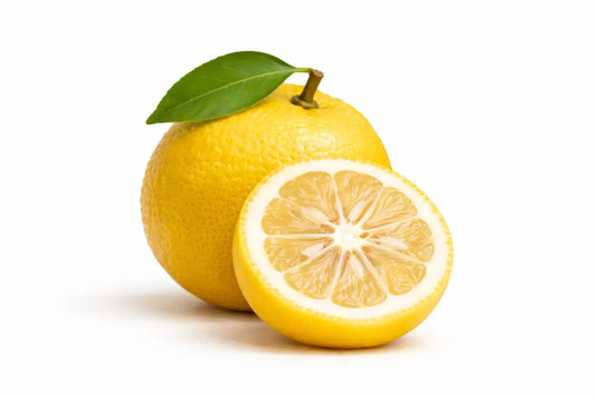 Un limón amarillo vibrante con una hoja verde fresca aún unida a su tallo, cortado por la mitad para revelar sus jugosos segmentos.