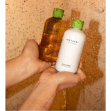 Dos botellas de té verde kintsugi, una ámbar y una blanca, ambas con tapas verdes.